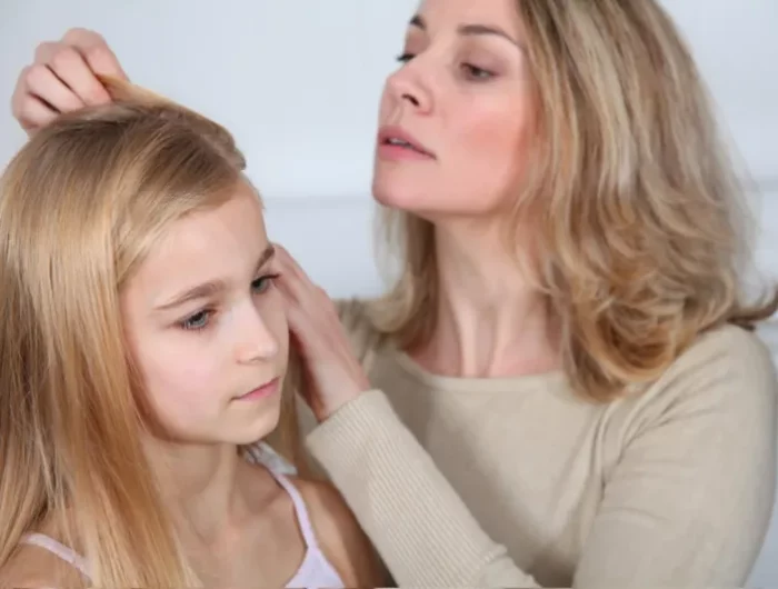 une femme inspecte les cheveux de sa fille pour des poux