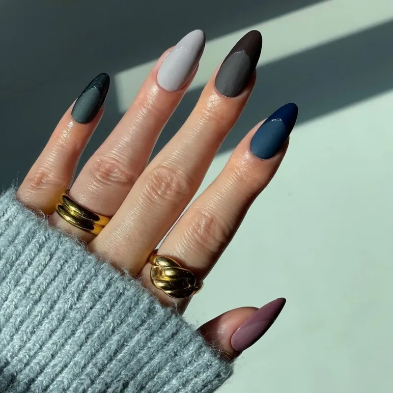 une maine avec ses doigts avec des bagues et ongles vernis de couleurs foncees brillant mat noir fris bleu prune