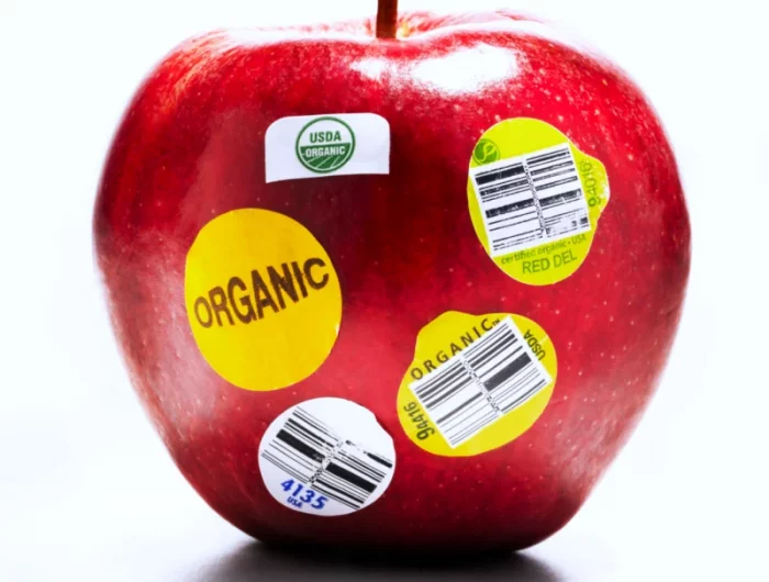 une pomme rouge avec des autocollants pour les pesticides