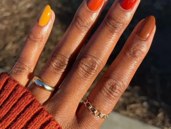 vernis automne de couleurs arc en ciel sur les doigts de la main avec une manche couleur orange brique