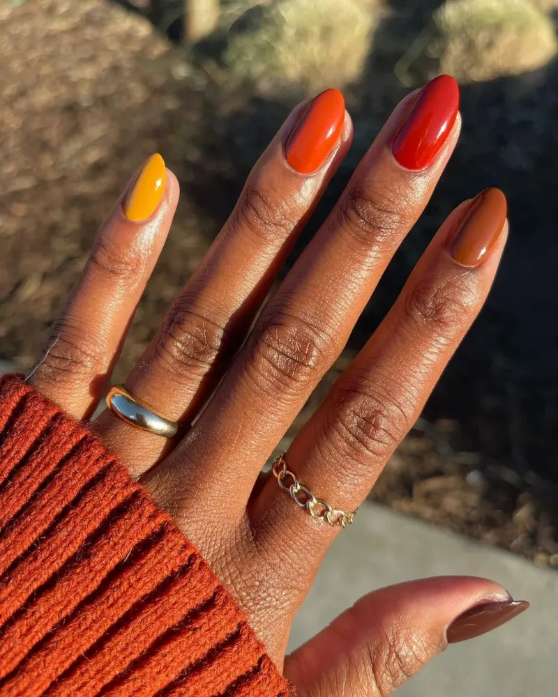 vernis automne de couleurs arc en ciel sur les doigts de la main avec une manche couleur orange brique