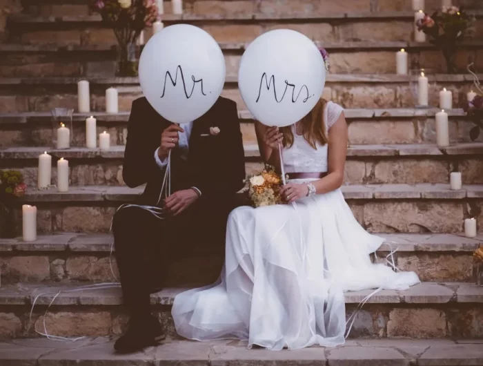 couple assis sur un escalier le jour de son mariage se cache derriere des ballons