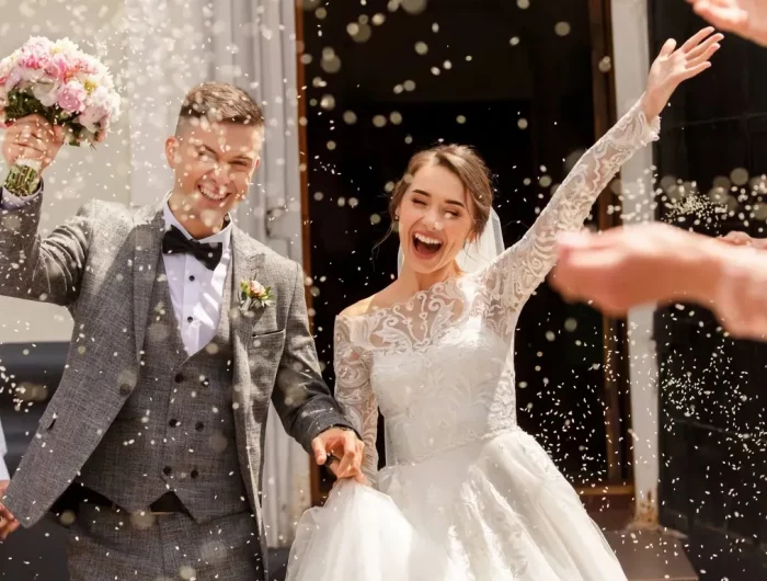 couple joyeux fraichement marie le jour de son mariage sous une pluie de riz