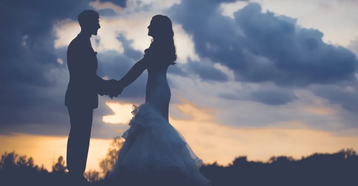 two silhouettes of brides on a sunset background with clouds