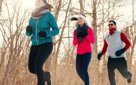 jogging entre amis dans le froid avec deux femmes en premier plan et un homme derriere elles sur fond un bois en hiver