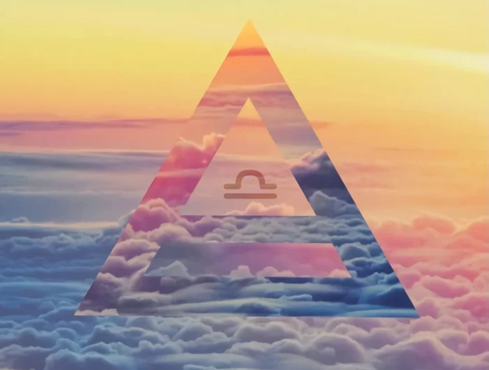 le symbole du signe astrologique de la balance inscrit dans un triangle sur fond le ciel au dessus des nuages
