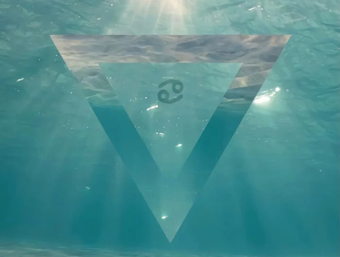 le symbole du signe astrologique du cancer inscrit dans un triangle sur fond de mer calme avec des rayons de soleil