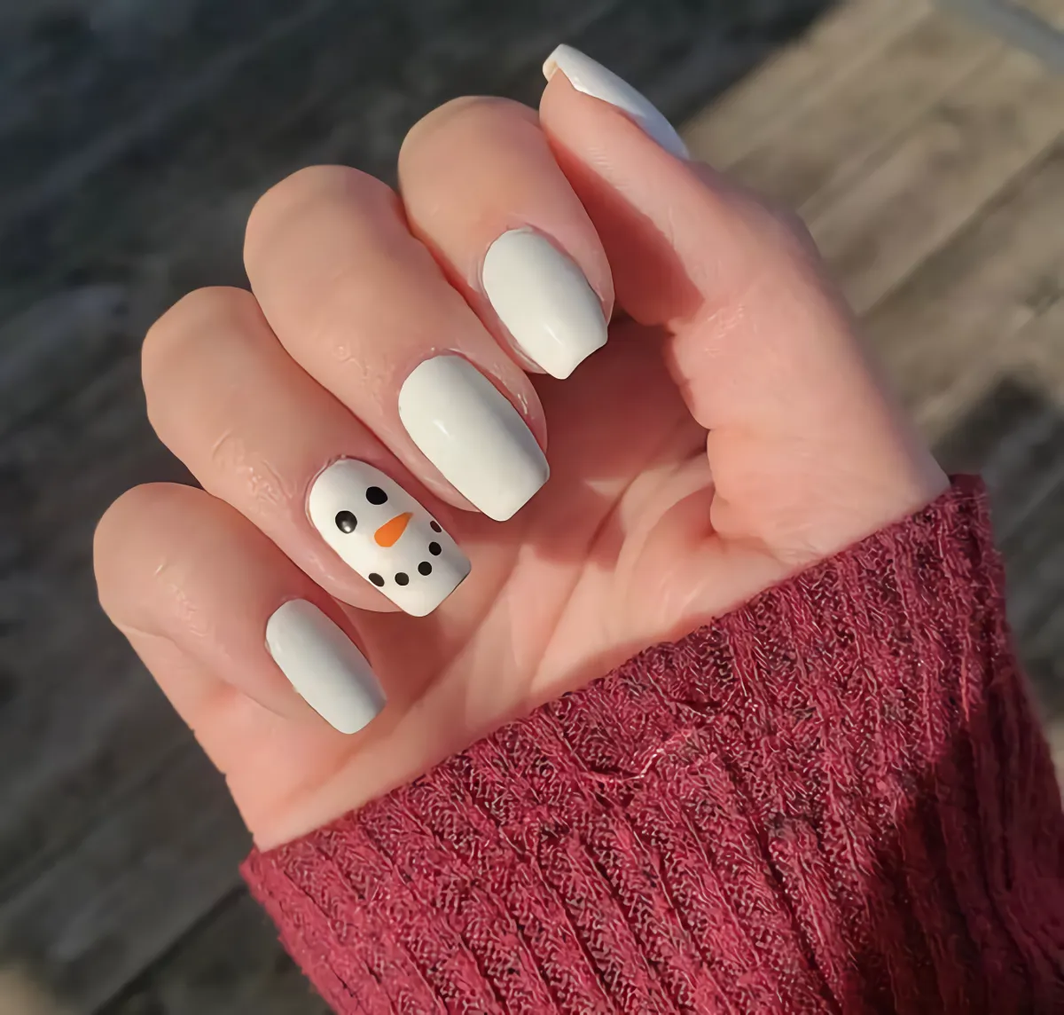ongles blancs avec un bonhomme de neige minimaliste sur un des ongles