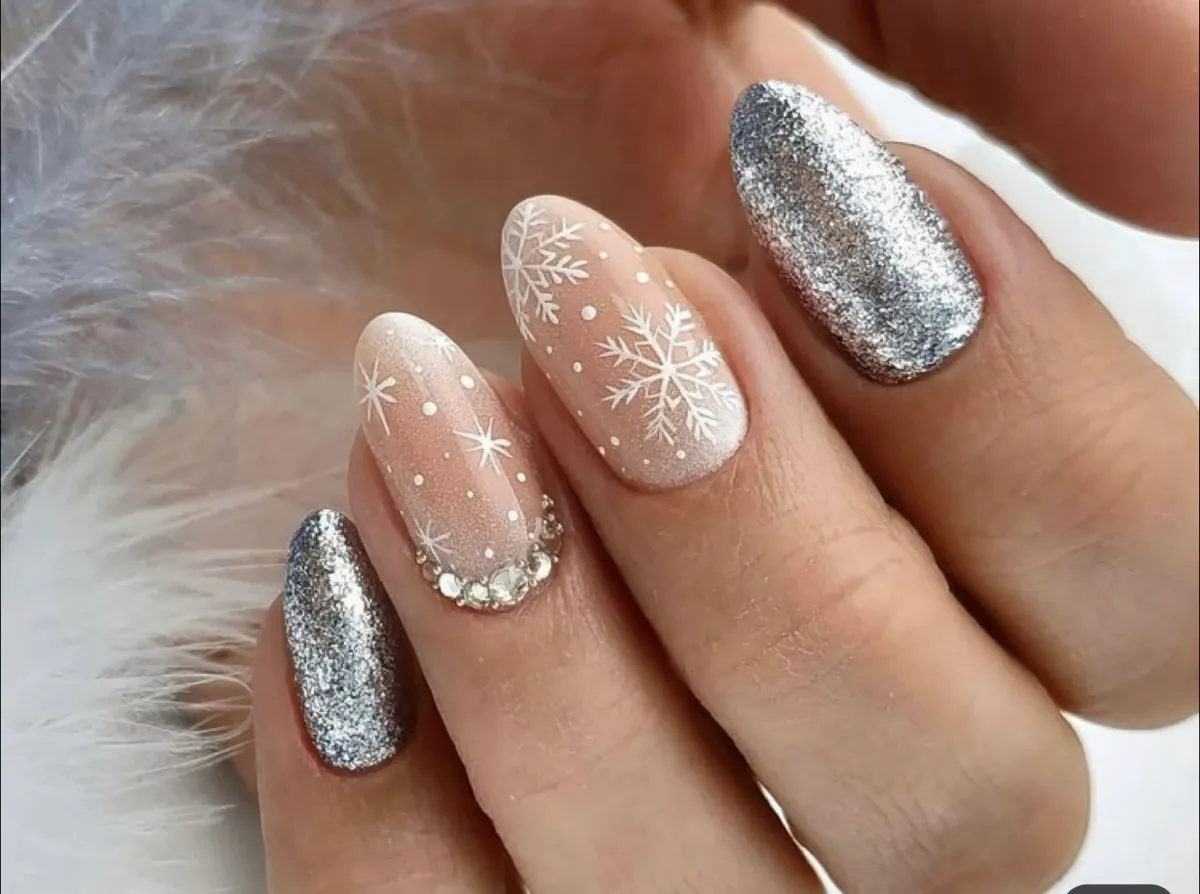 ongles noel scentillants avec deux ongles argentes et deux couleurs peau avec des flocons blancs et des petites pierres transparents et brillants
