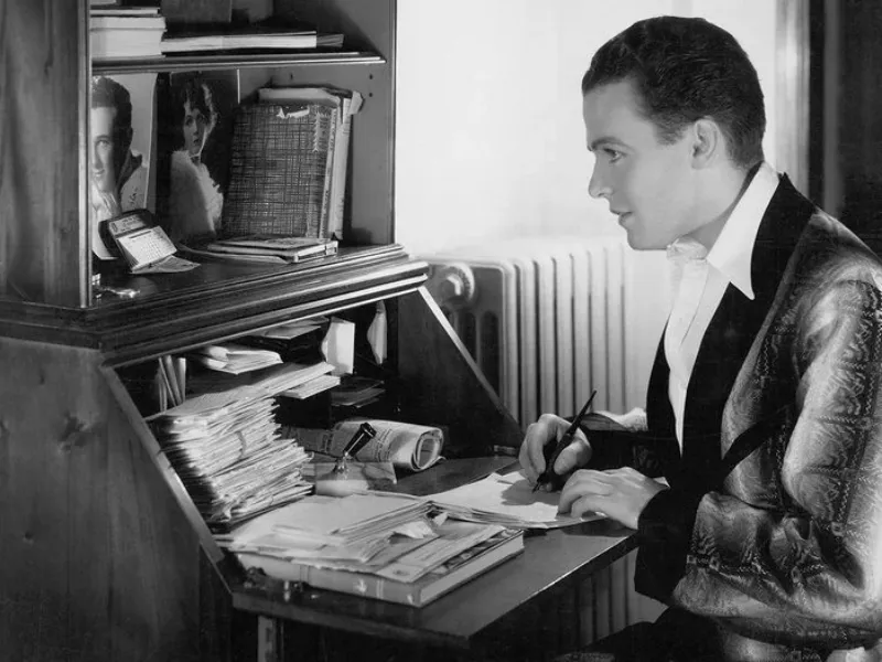 photo en noir et blanc et un homme qui ecrit une lettre