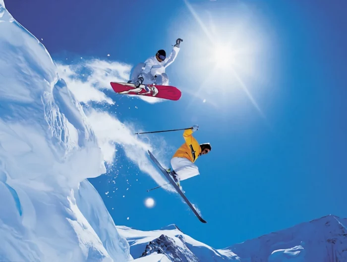 saut au dessus des rochers de snowboarder et skieur sur fond de ciel bleu ensoleille