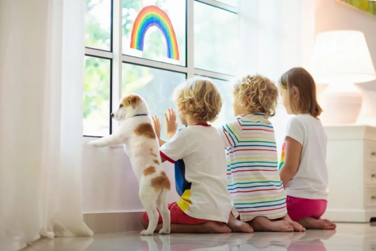 trois enfants avec un petit chien regardent par la fenetre assis sur un sol brillant dans un interieur blanc