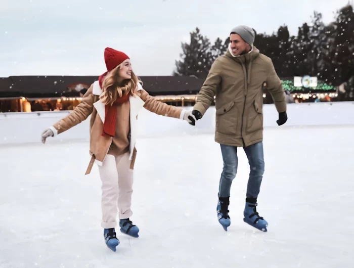 un couple souriant qui fait du patin a glace dehors en hiver