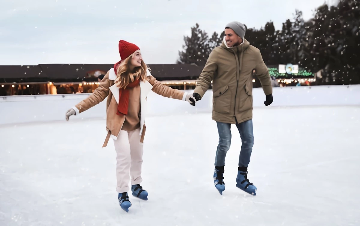 un couple souriant qui fait du patin a glace dehors en hiver