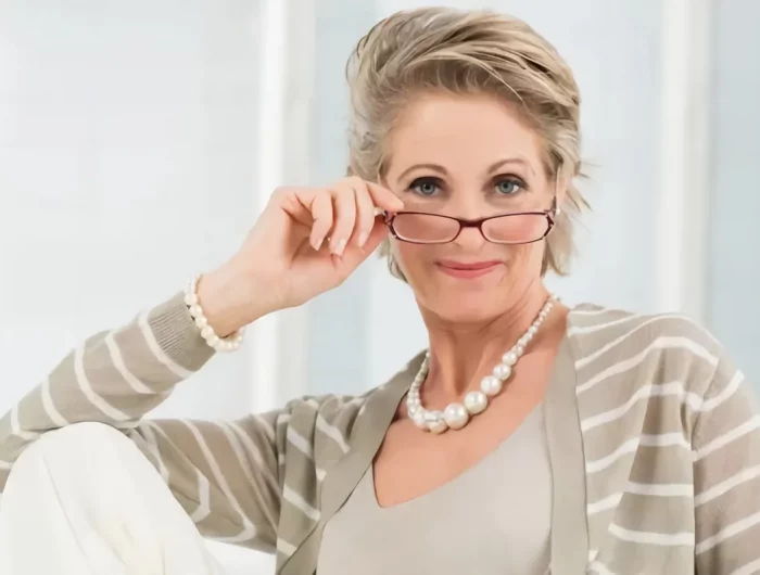 les meilleures coiffures de 2023 pour dames après 60 ans avec des lunettes femme aux lunettes gilet beige