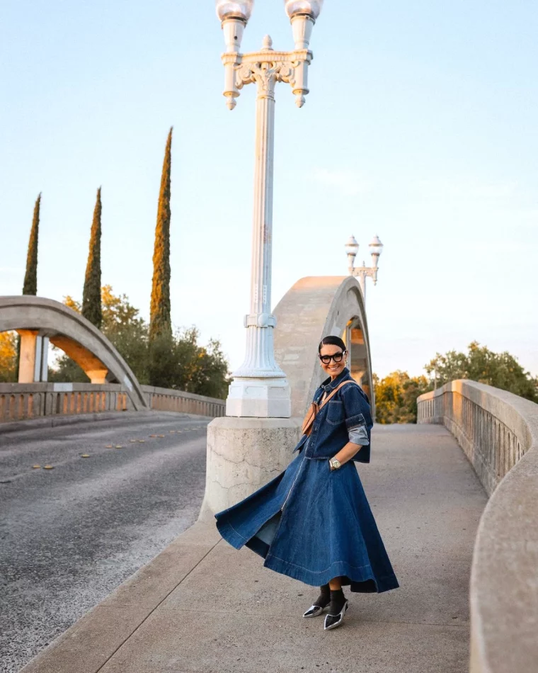 femme 60 ans habille chic jupe et veste en jean sur un pont