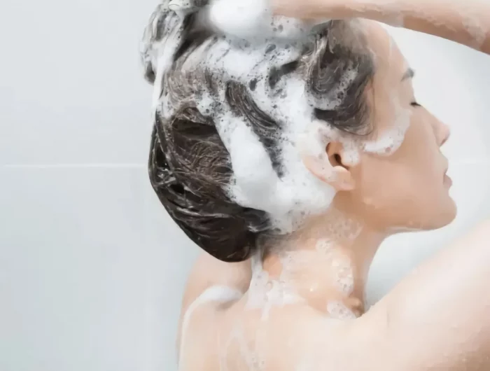 femme qui mousse ses cheveux sous la douche