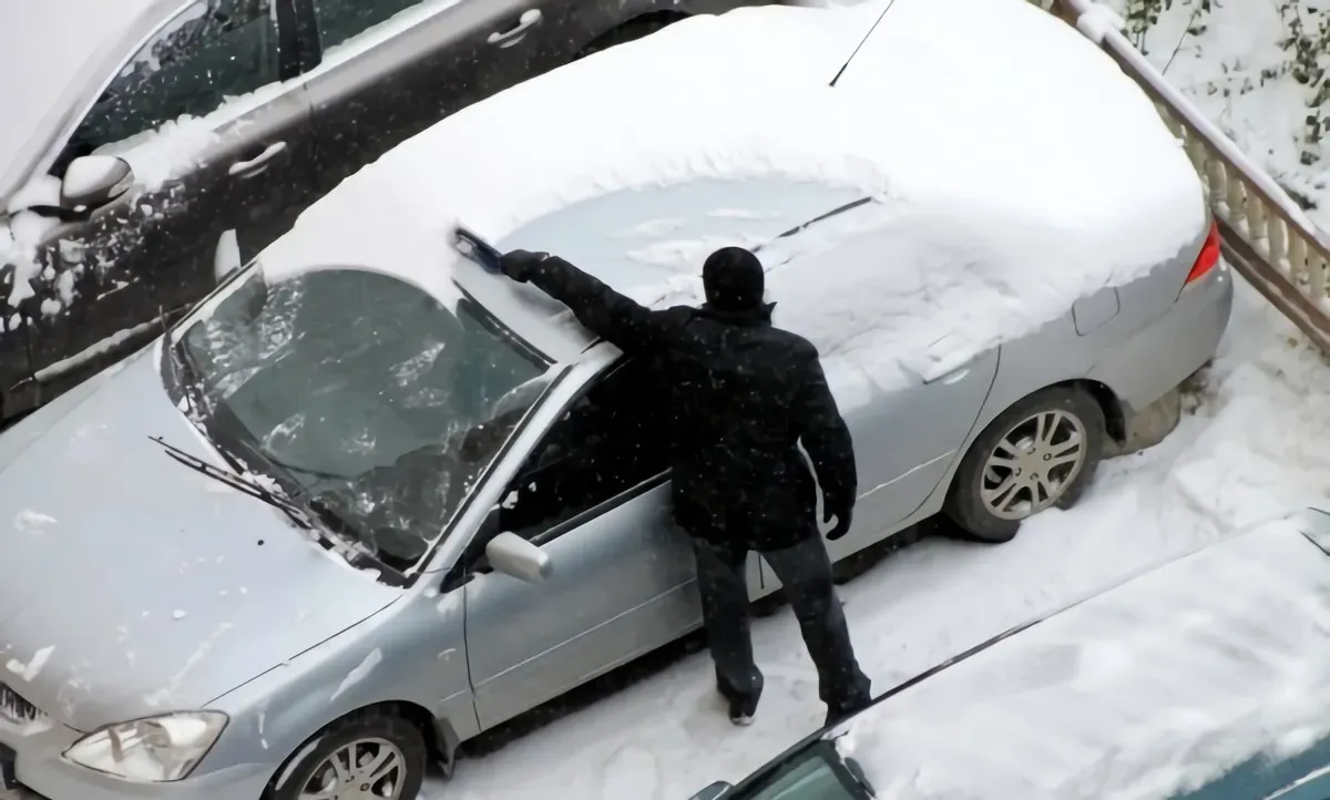 la mailleur facon enlever la neige de votre voiture pas a pas avec une vue de dessus un homme qui nettoie sa voiture