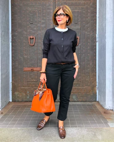 total look noir mode femme 60 ans avec un sac orange