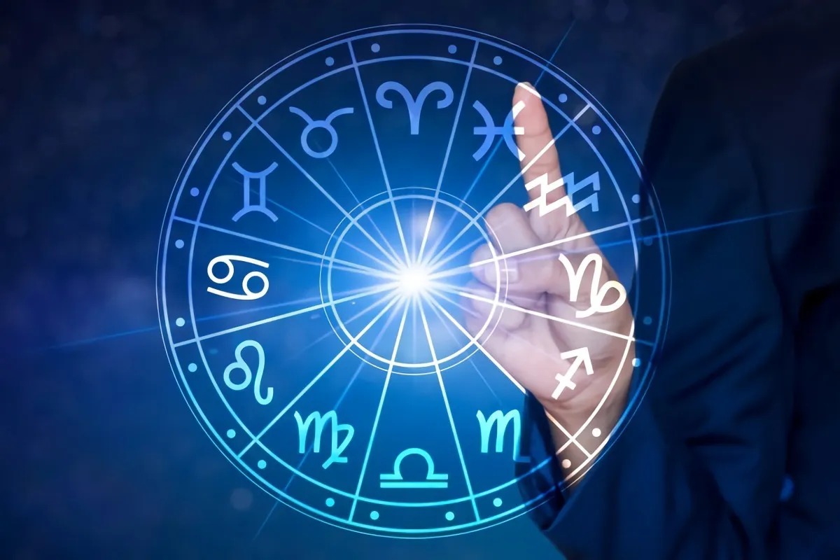 un doigt qui montre le signe des poissons sur un zodiaque au milieu duquel est le soleil qui brille sur fond de ciel bleu