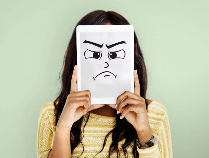 une femme aux cheveux longs bruns qui tient une pancarte exprimant une mauvaise humeur