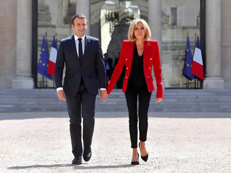 brigitte macron en jeans et veste rouge main dans la main avec son mari