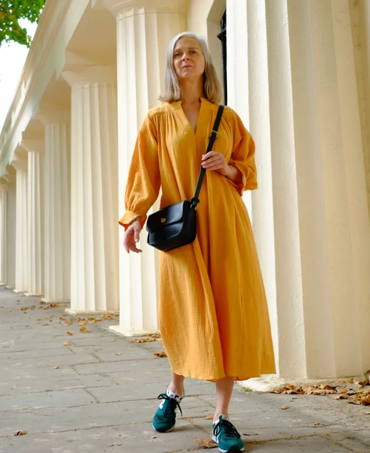baslkets bleus avec une robe jaune et sac à main tendance noire tenue femme stylée 60 ans