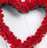 couronne en forme de cœur faite de roses rouges sur fond de planches en bois peintes en blanc