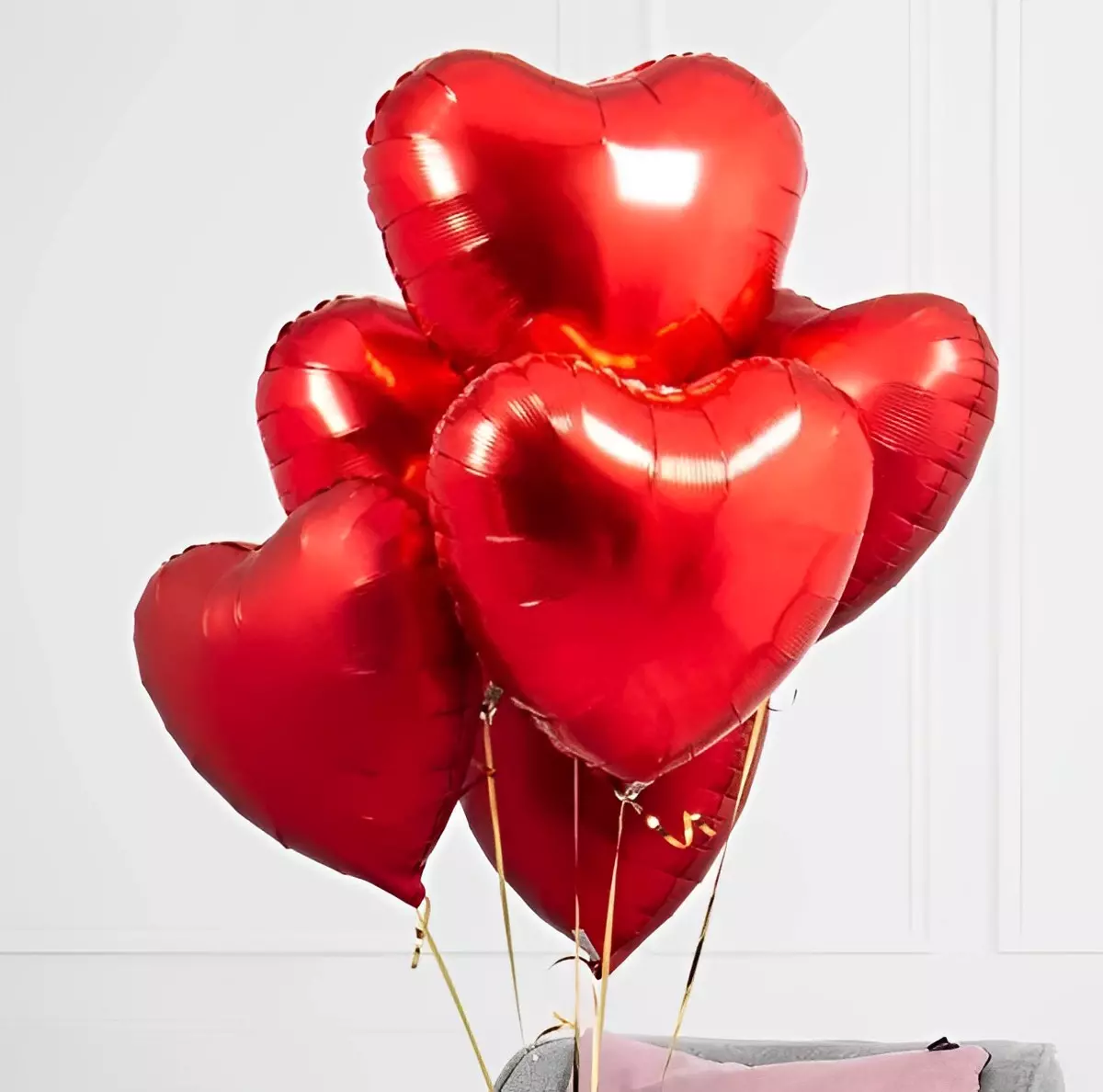 des ballons rouges en forme de cœurs attaches audessus du lit sur fond blanc