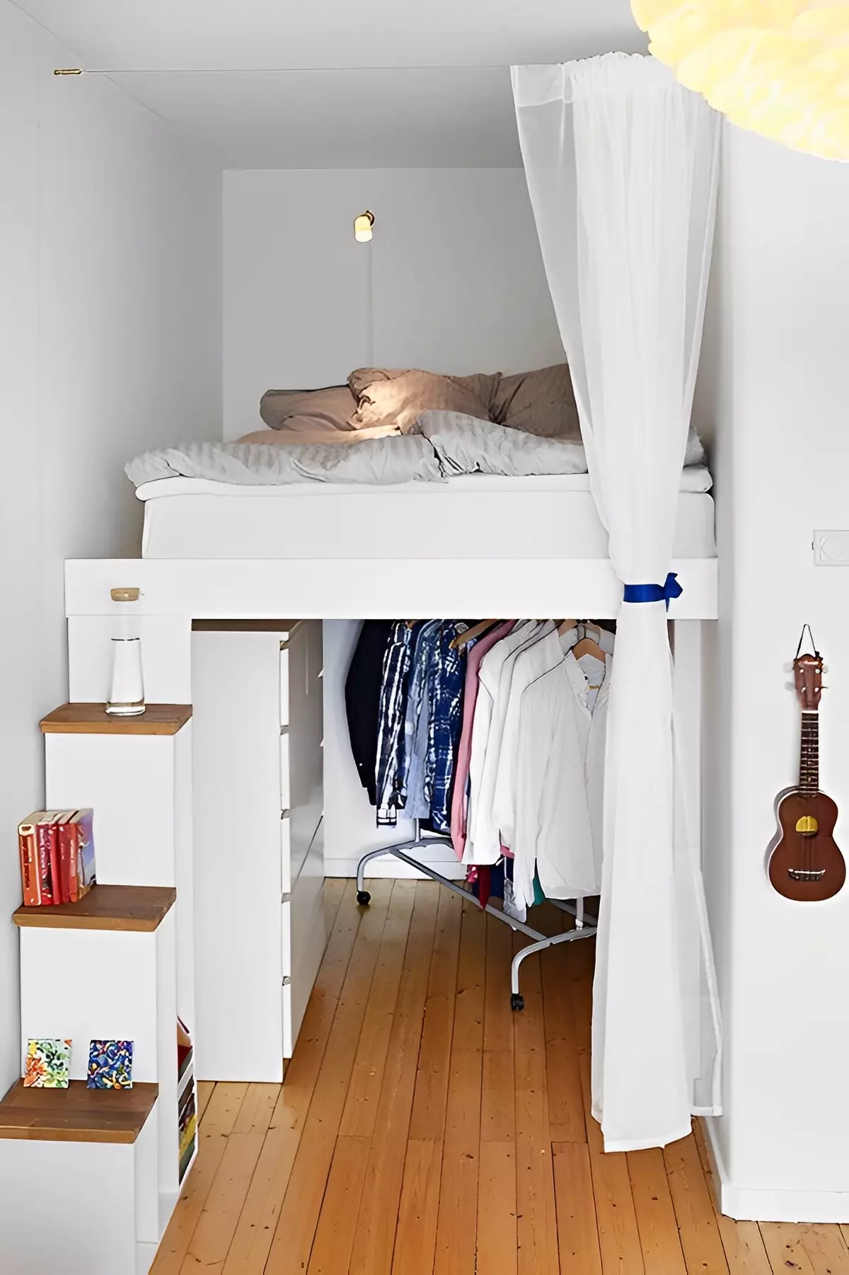 lit en mezzanine avec un meuble escalier et un portant de vêtement au dessous du lit