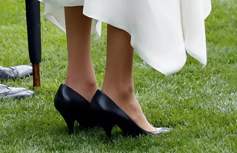 petits pieds dans de grandes chaussures noires sur une pelouse verte avec une robe blanche