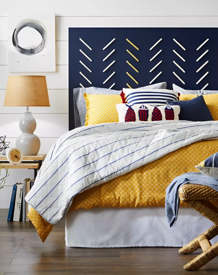 une tete de lit bleu nuit a motifs avec un lit et beaucoup de coussins colores