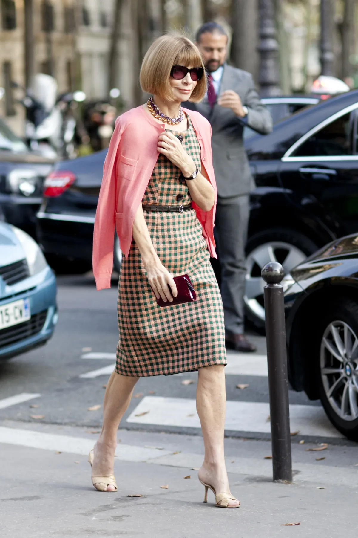 Anna Wintour camina por las calles con un vestido de largo medio con un cardigan rosa
