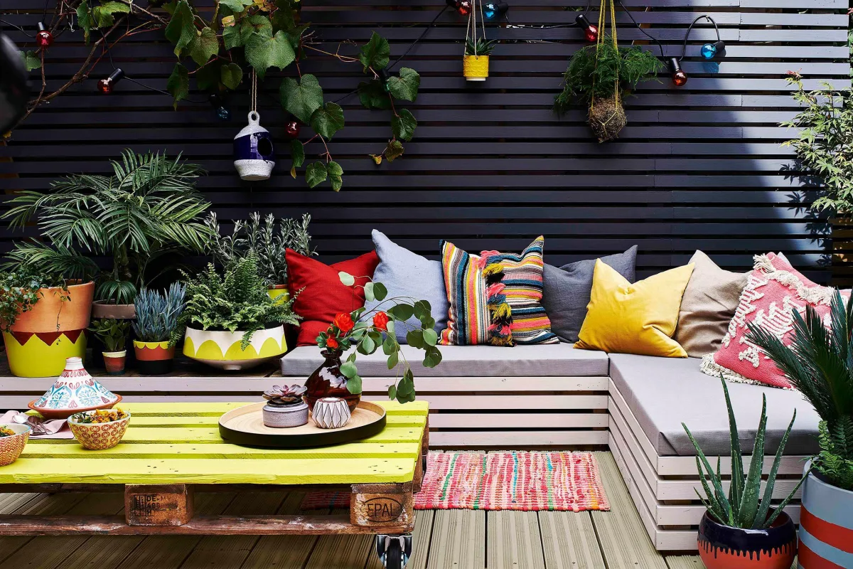 canapé d angle en bois coussins colorés table basse palette avec plateau peint en jaune plantes vertes