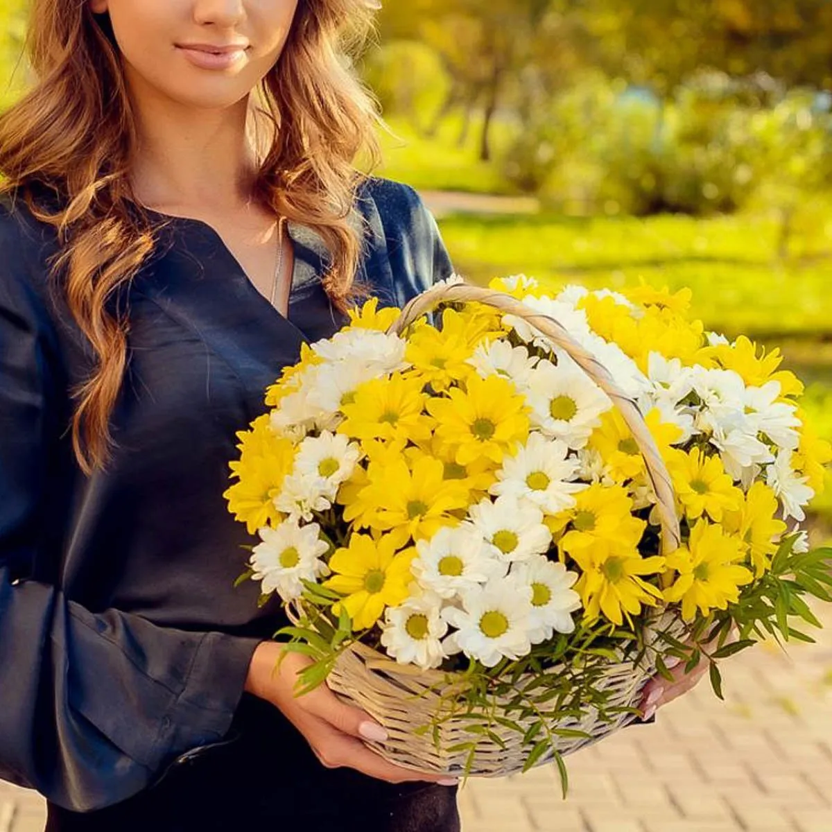 mujer sosteniendo crisantemos en macetas en cesta de flores