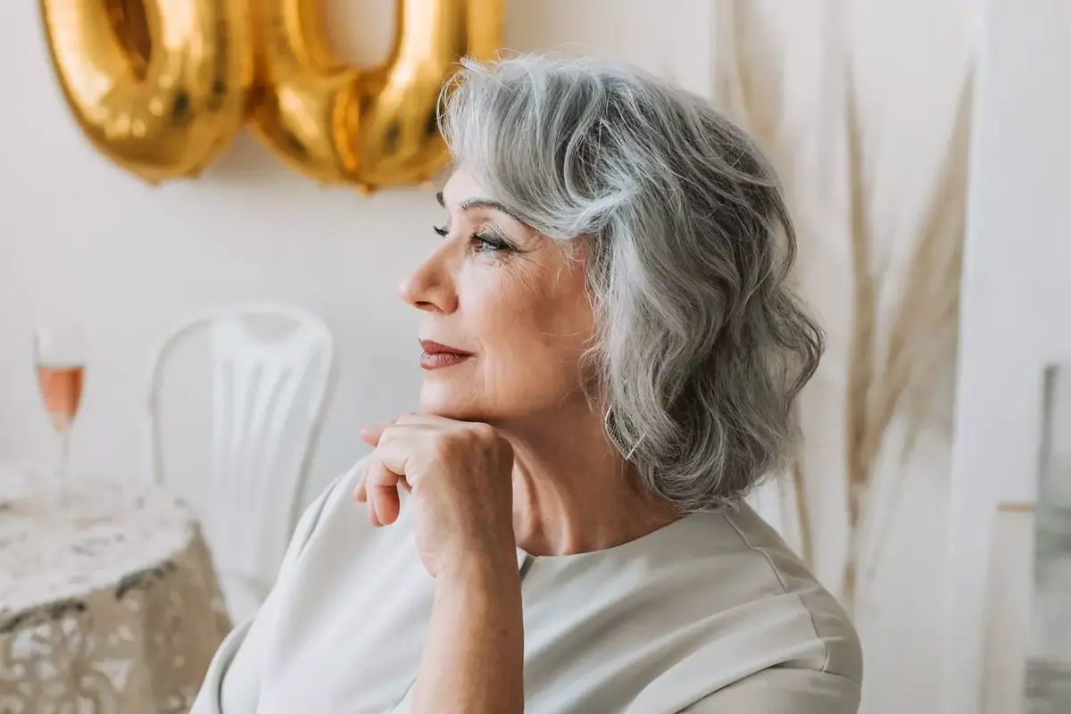 femme de 60 ans cheveux gris dans son salon