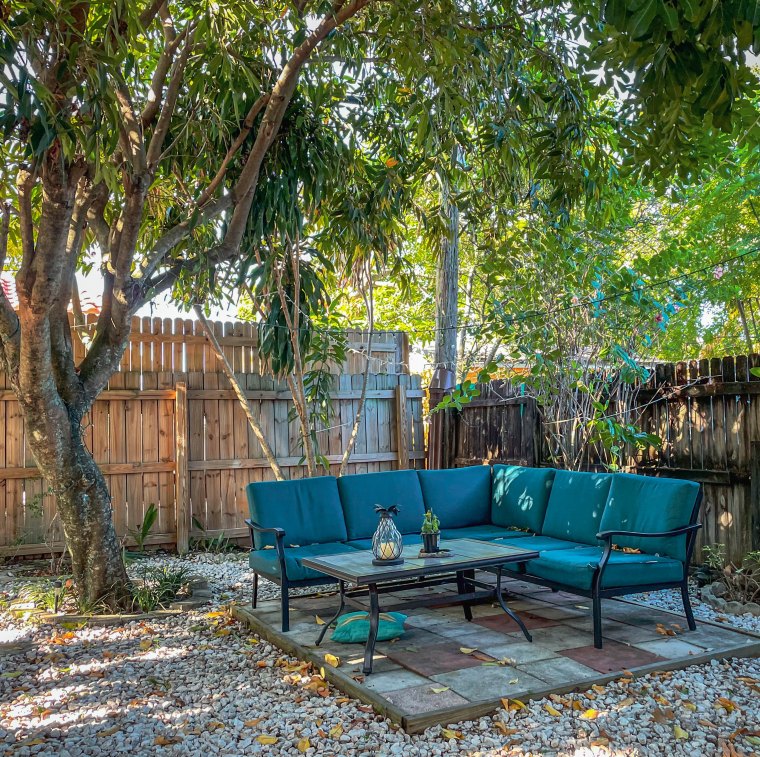 jardin paysager sans entretien avec gravier terrasse de dalles de pierre table basse et meuble canapé d angle cloture de bois