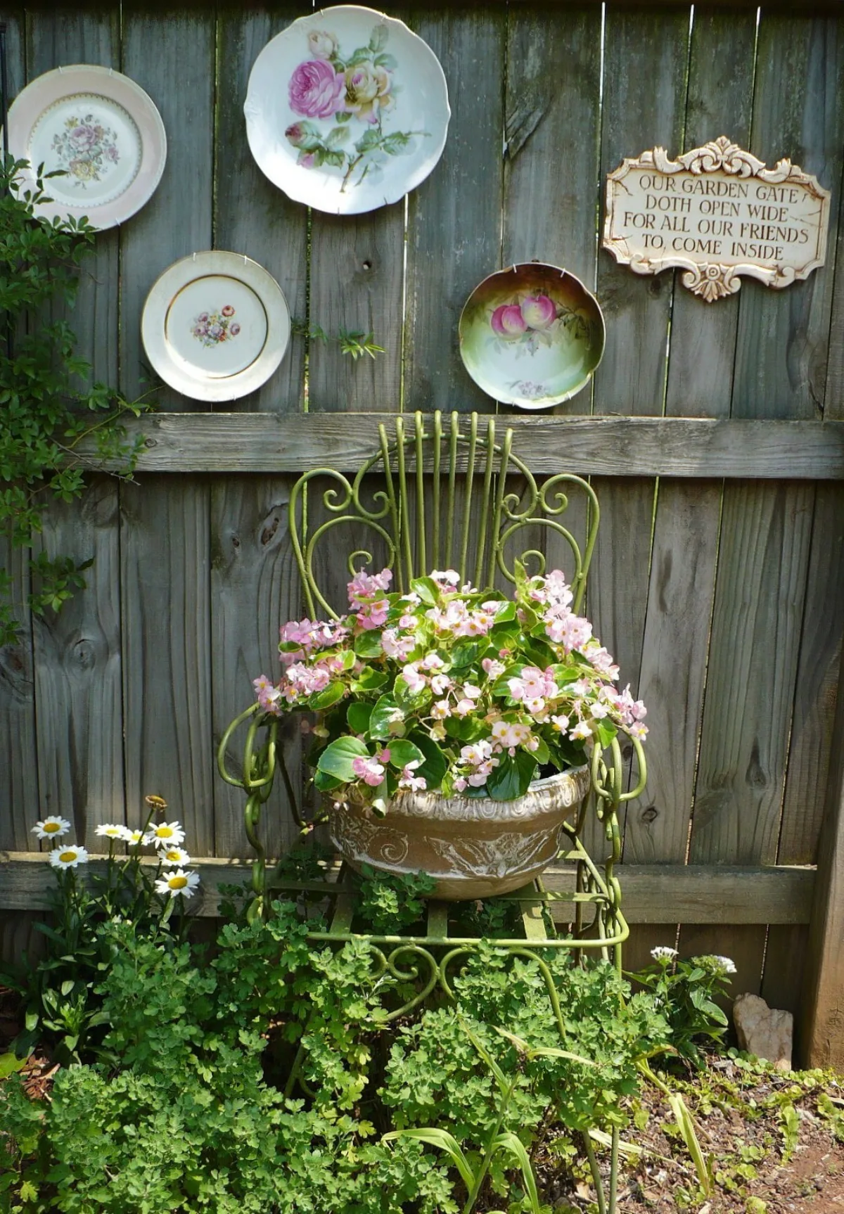 separation de jardin palissade de bois décorée de vaisselle ancienne chaise et pot de fleur