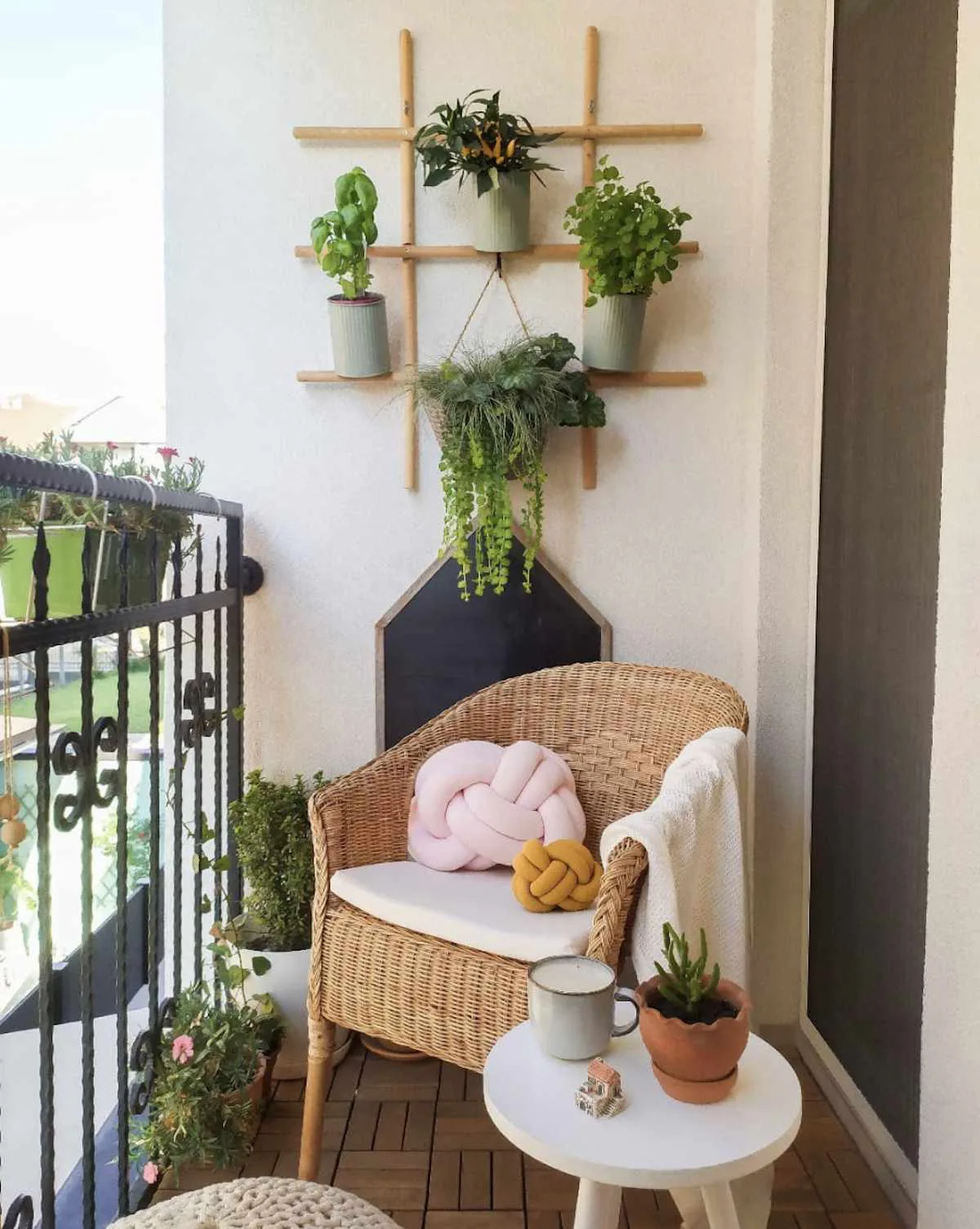 balcon aménagé avec fauteuil en rotin table basse blanche étagère plantes suspendues
