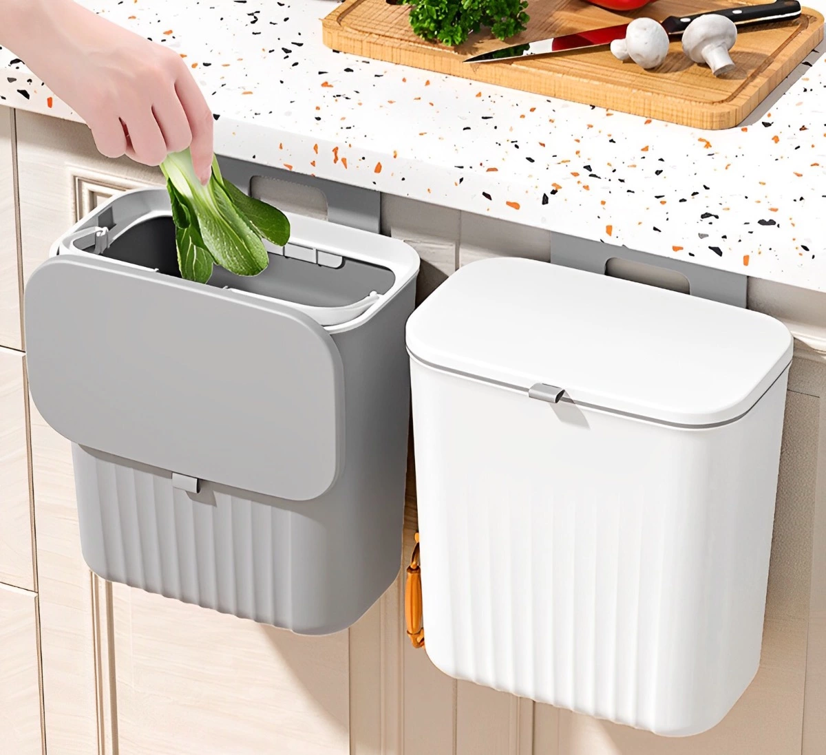 deux poubelles a couvercles une blanche a droite et une grise a gauche accrochees au meuble de cuisine