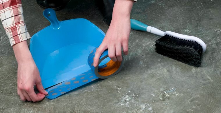 mettre du scotch au bout d une pelle bleue et un balai sur un sol gris avec des verres casses