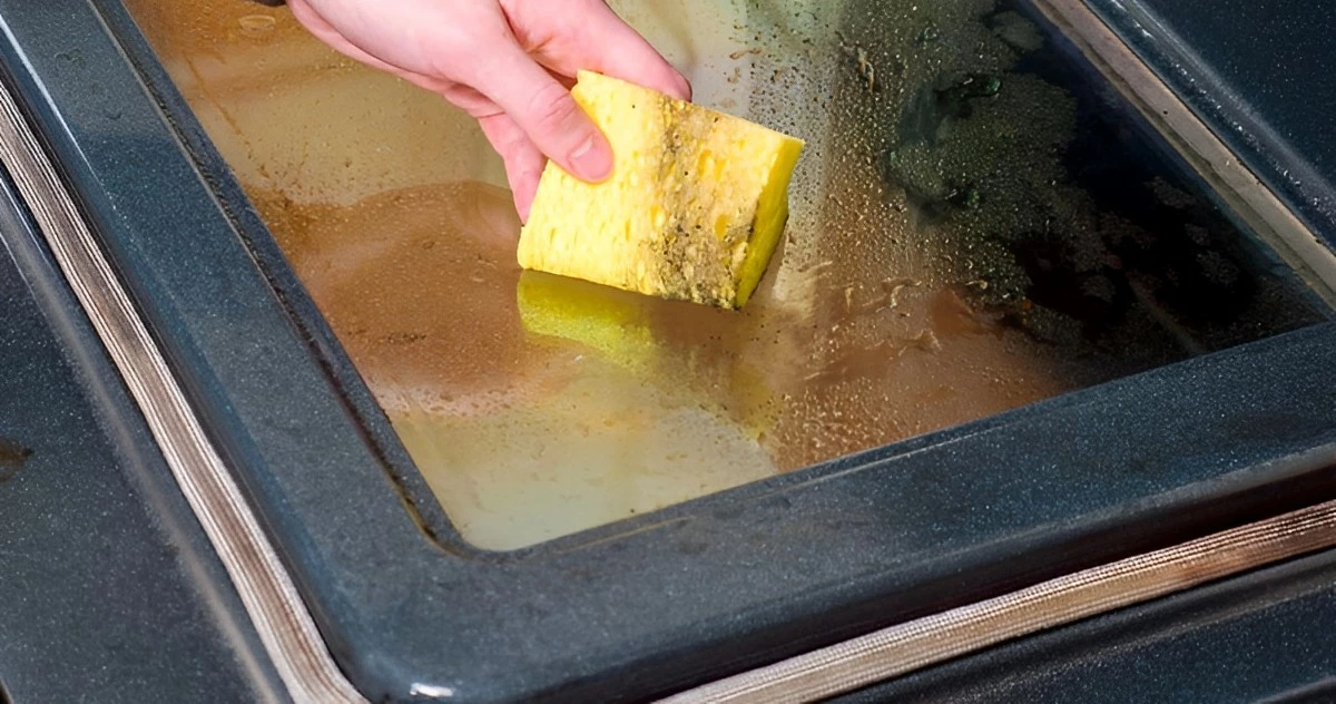 nettoyer la porte d un four tres sale avec un eponge jaune