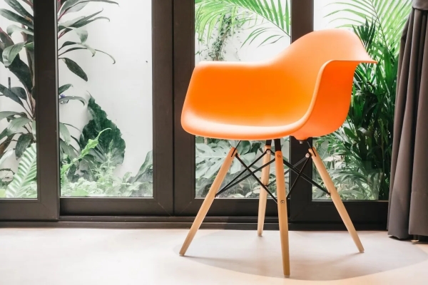 plante verte fenetres rideaux gris fonce chaise orange plastique pieds bois