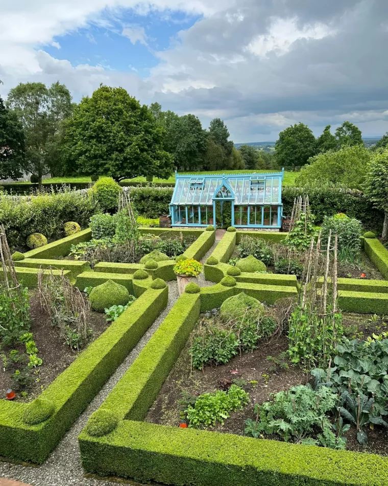 serre en forme de maison en bleu carres potager entoures de petites haies