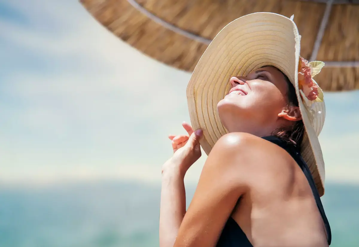 femme avec un chapeau exposee au soleil comment eviter le vieillissement de la peau