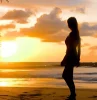 silhouette feminine a la plage sur fond du soleil couchant