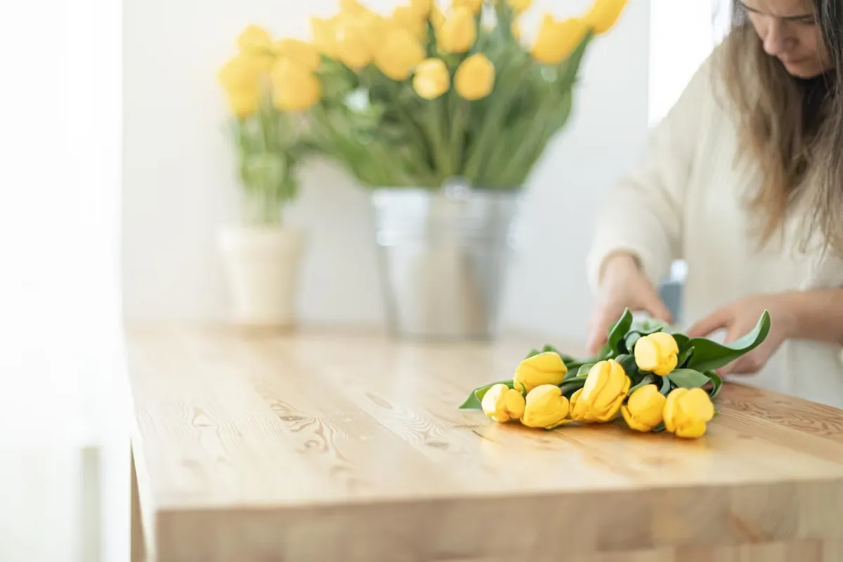fleuriste composition florale tulipes jaunes surface bois plan de travail
