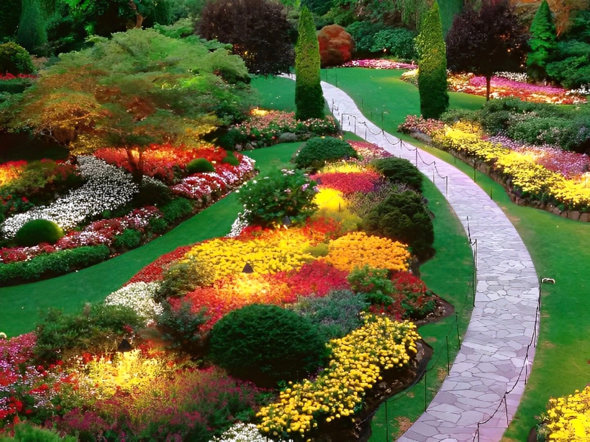 jardin paysager avec un chemin qui traverse a cote d un massif avec une combinaison de couleurs harmonieuse avec jaune rouge orange et différents nuances du vert