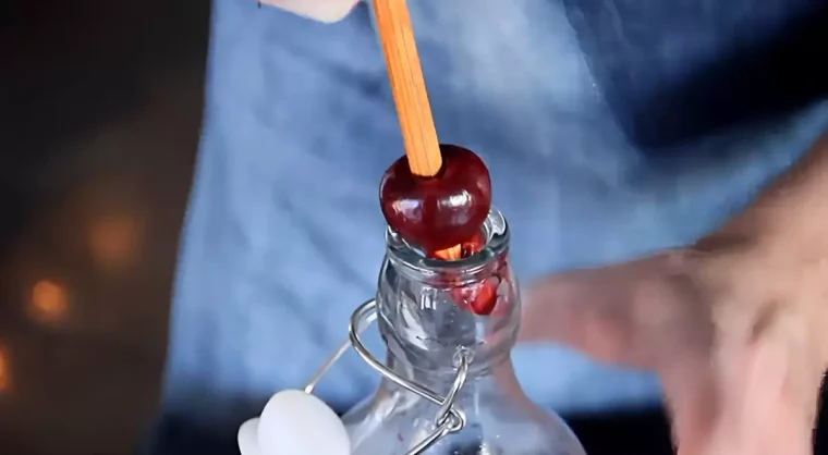 denoyauter une cerise sur l embout d une bouteille avec une baguette en bois