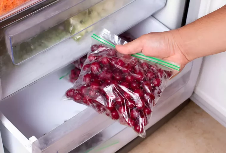 cerises dans un sachet plastique devant le bac du congelateur